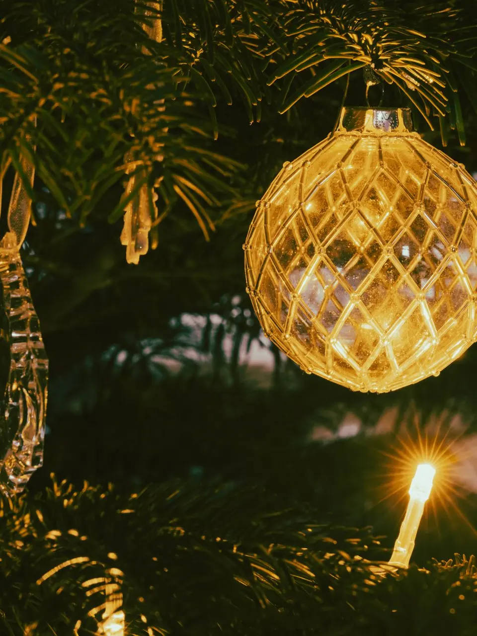 A gold crystal ornament glowing on a Christmas tree