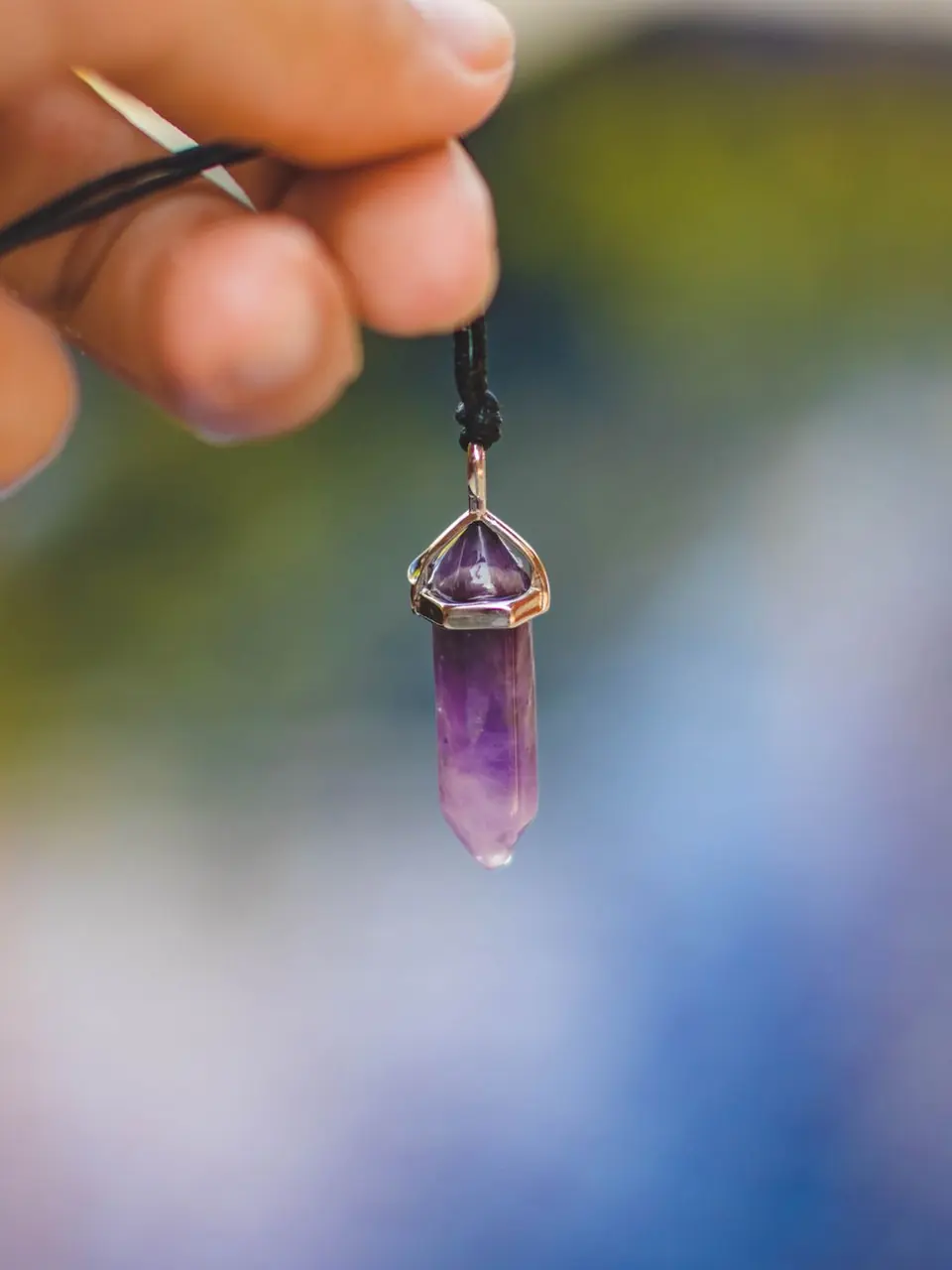 An amethyst point pendant held up to the light