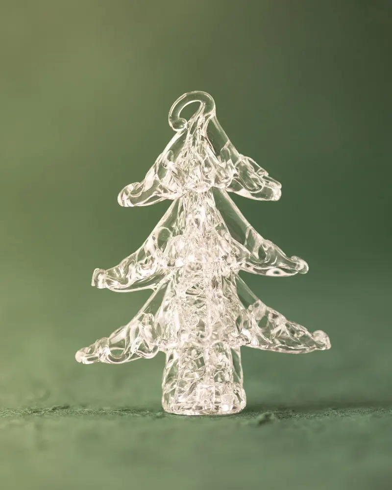 A clear glass Christmas tree ornament on green