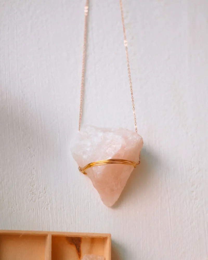 A raw rose quartz pendant wire-wrapped on a fine chain
