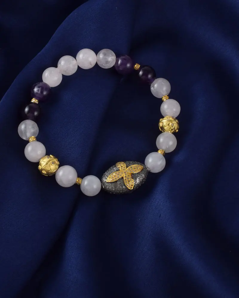 A bead bracelet of white stones with amethyst accents on navy fabric