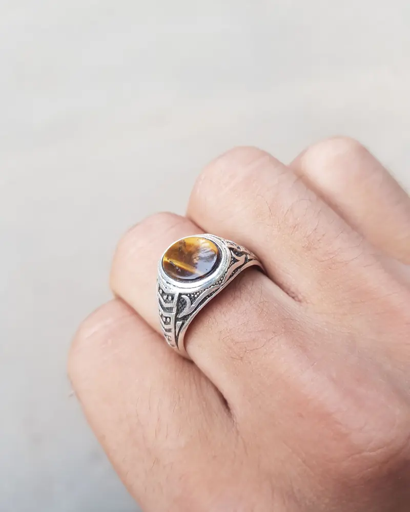 A sterling silver ring with a tiger's eye stone, worn on a hand
