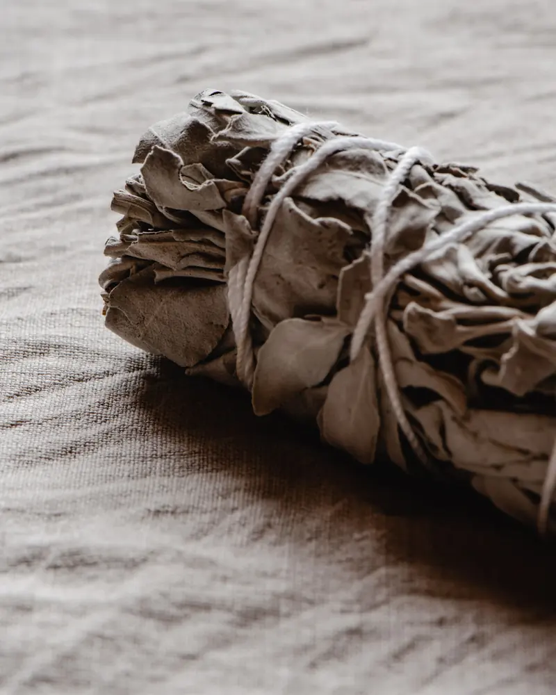 A tied white sage bundle on linen
