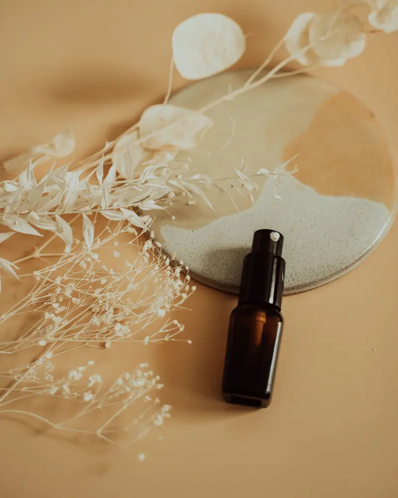 An amber glass oil bottle with dried flowers